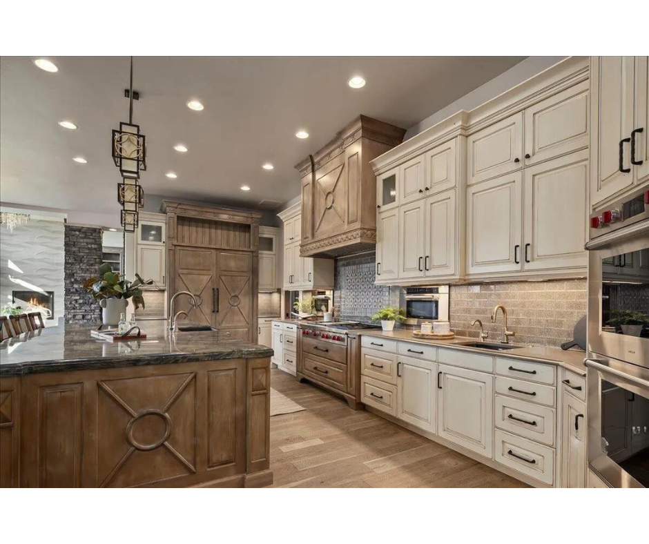 A kitchen with white cabinets , wooden floors , stainless steel appliances and a large island.
