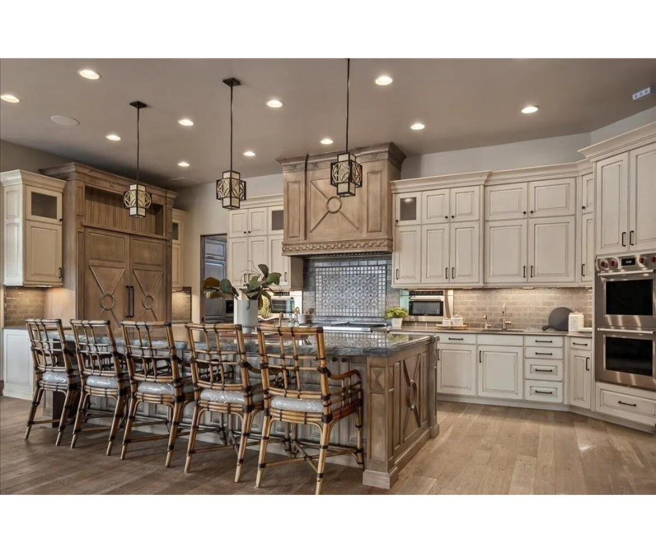 A kitchen with white cabinets , wooden floors , stainless steel appliances and a large island.