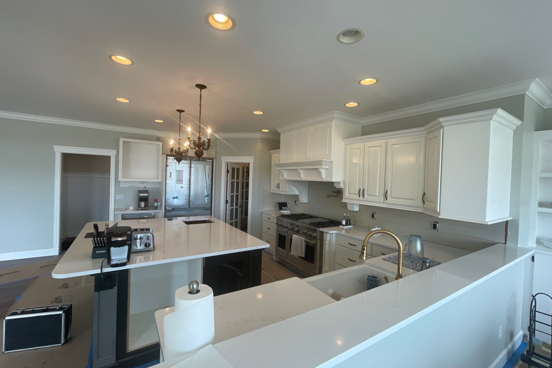 A kitchen with white cabinets , stainless steel appliances , and a large island.