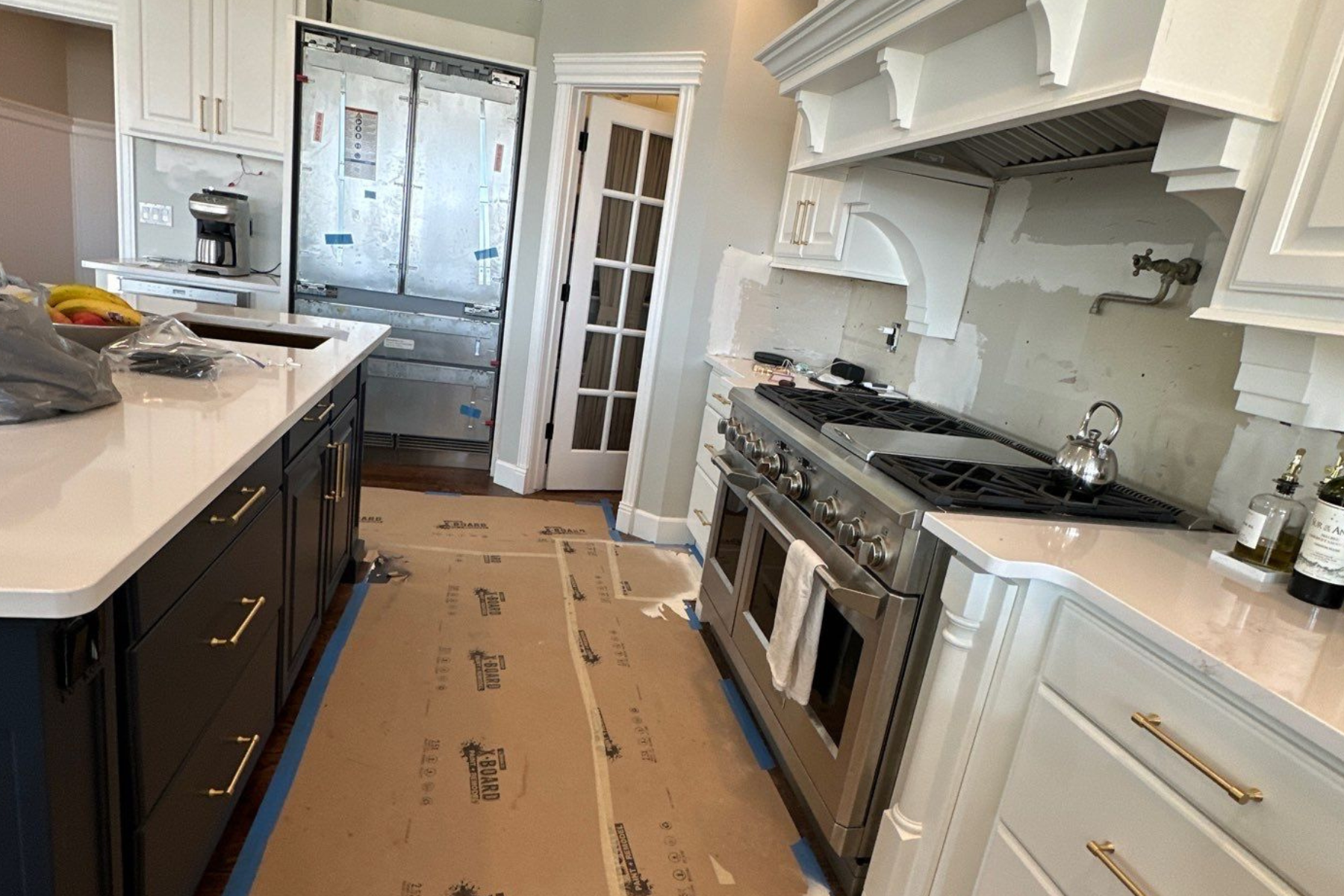 A kitchen with stainless steel appliances and white cabinets is being painted.