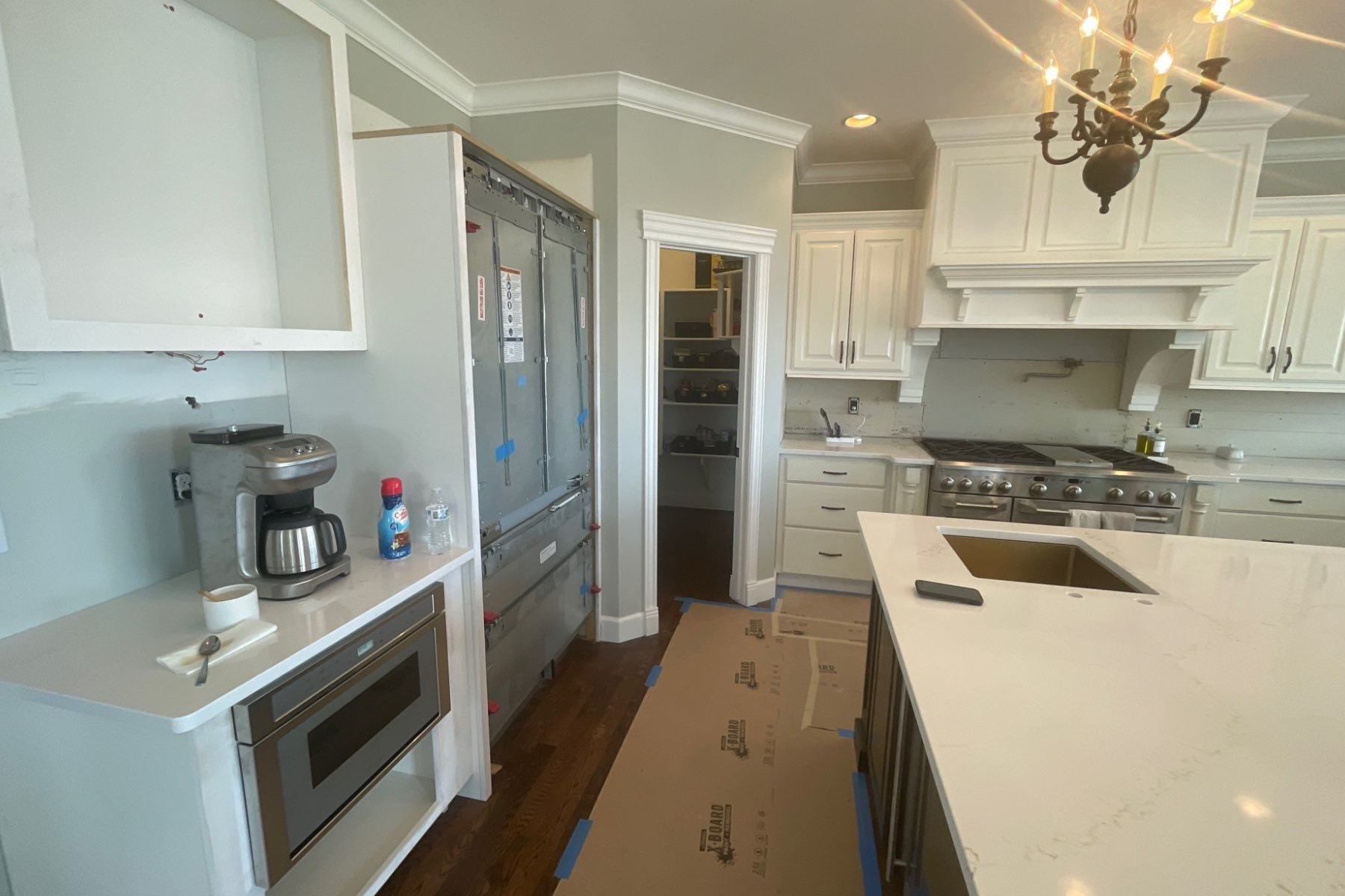 A kitchen with white cabinets and stainless steel appliances is being remodeled.