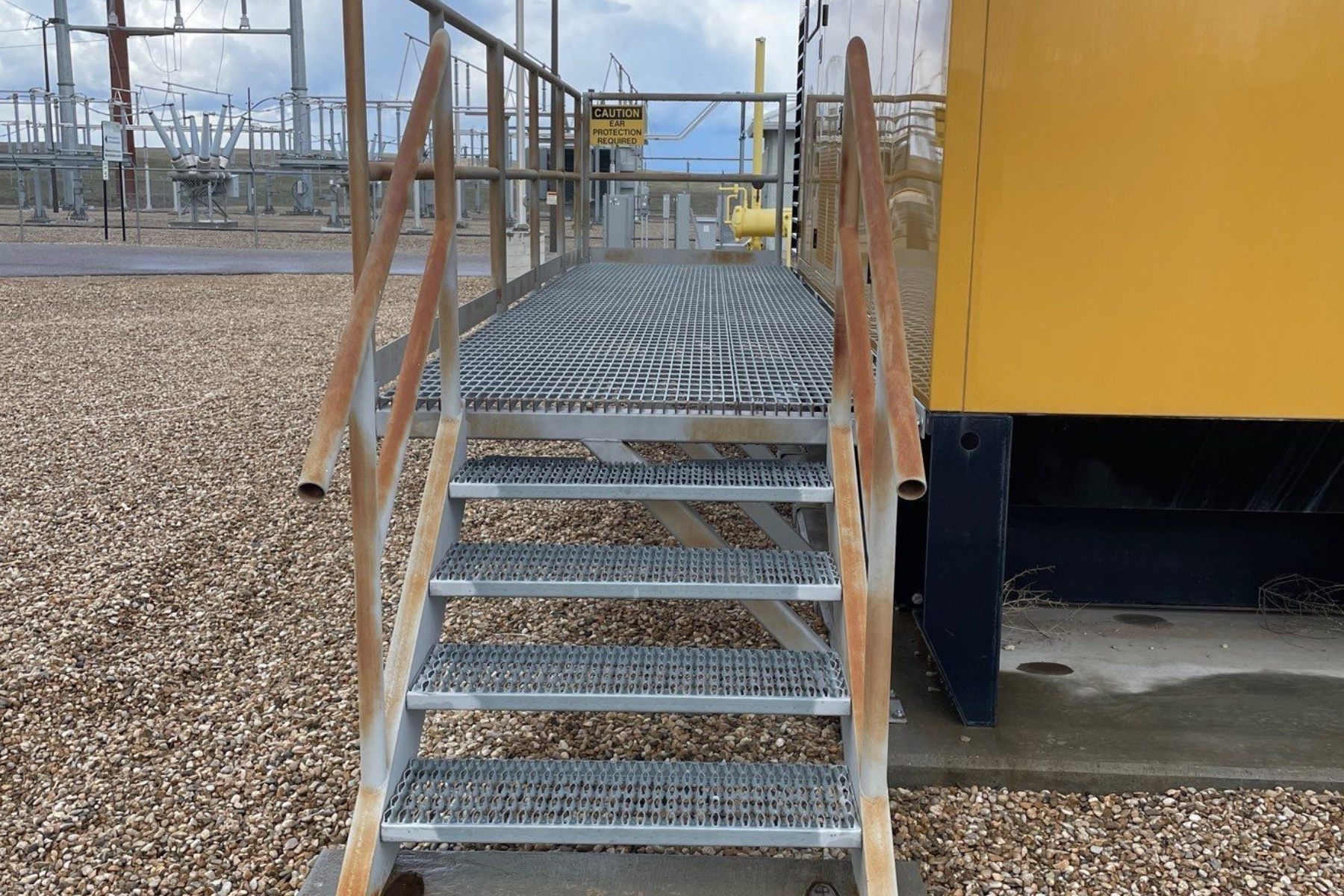 A set of metal stairs leading up to a yellow building.