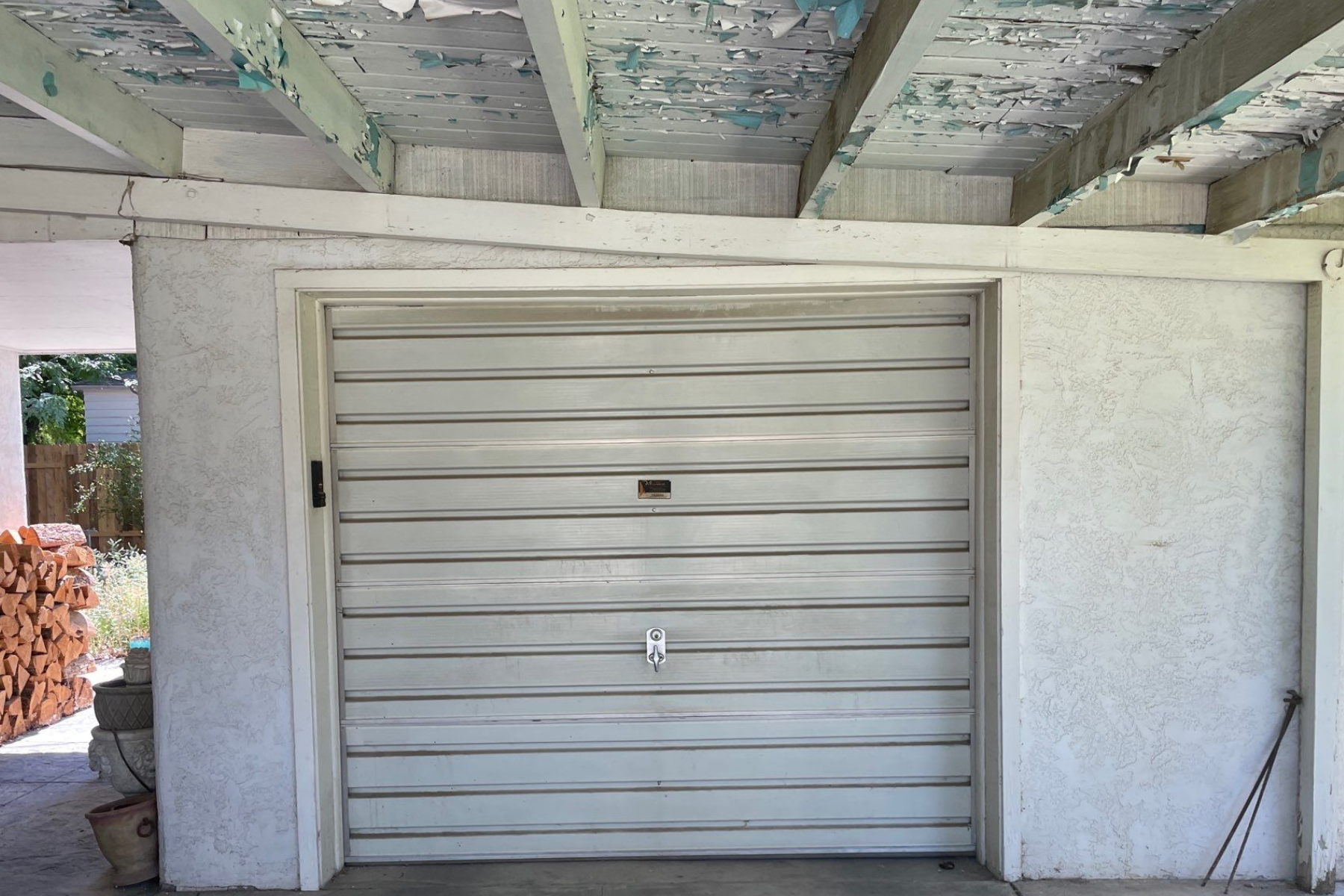 A white garage door is sitting under a wooden roof.