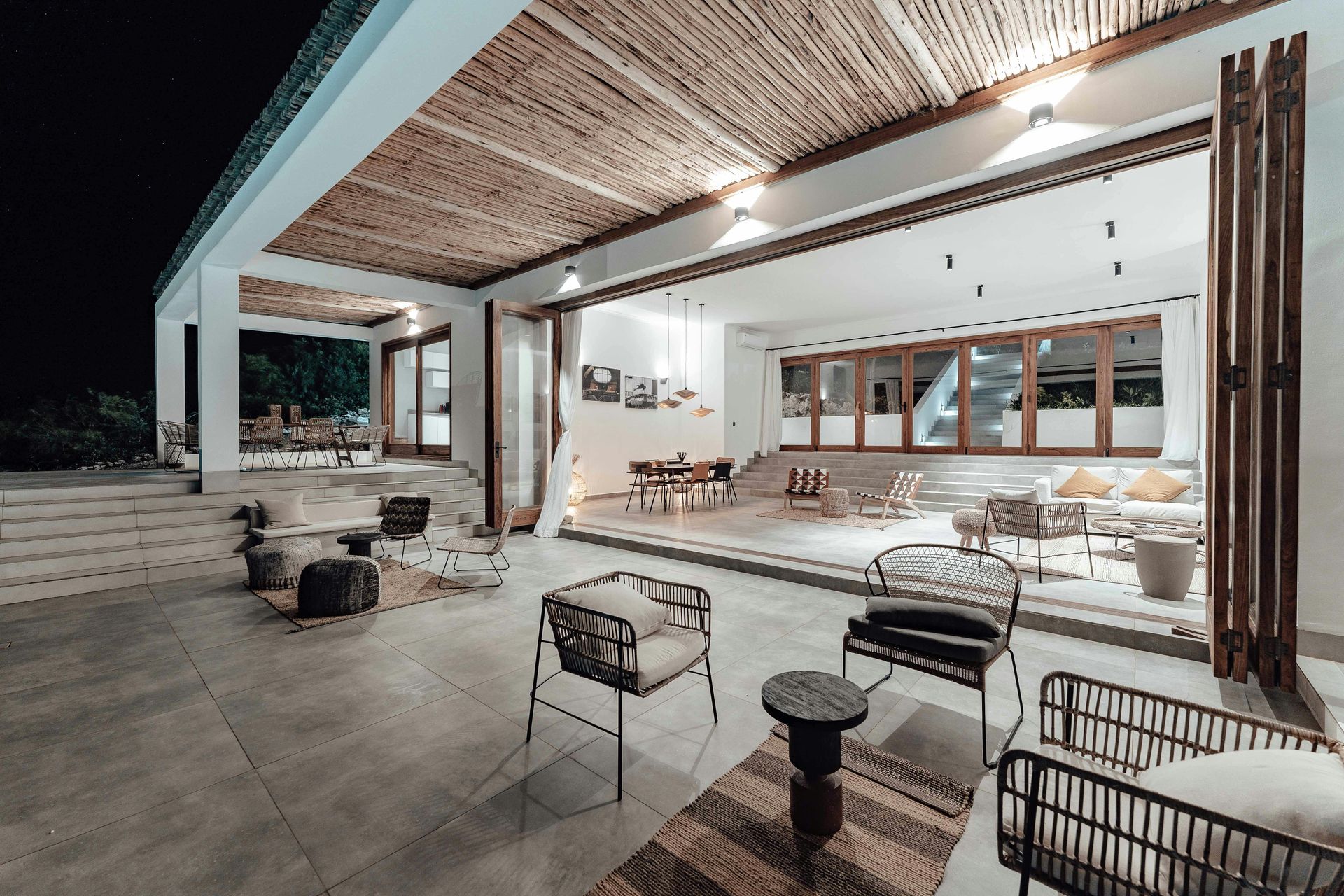 A living room with a lot of furniture and a covered patio at night.