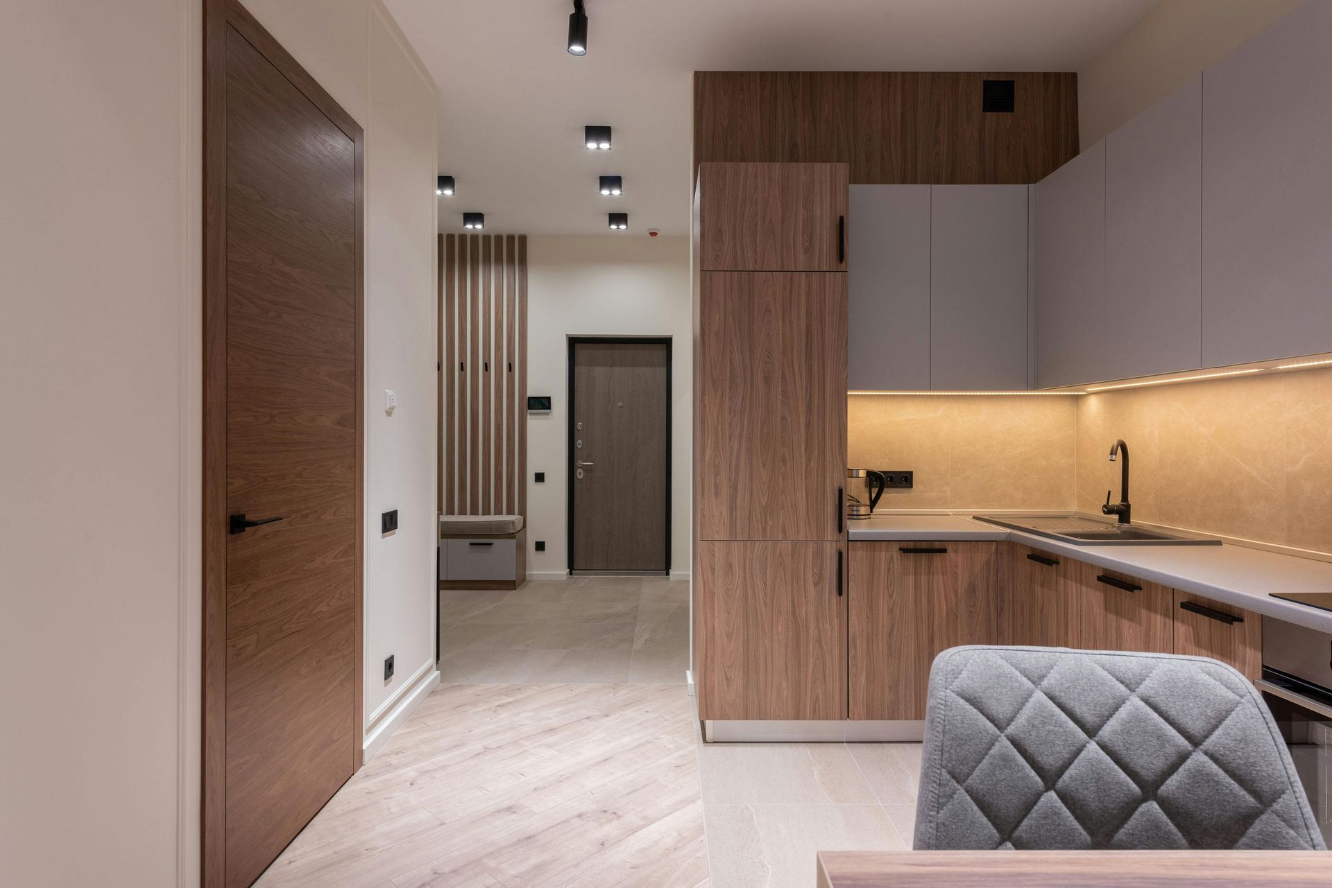 A kitchen with wooden cabinets , a sink , and a chair.