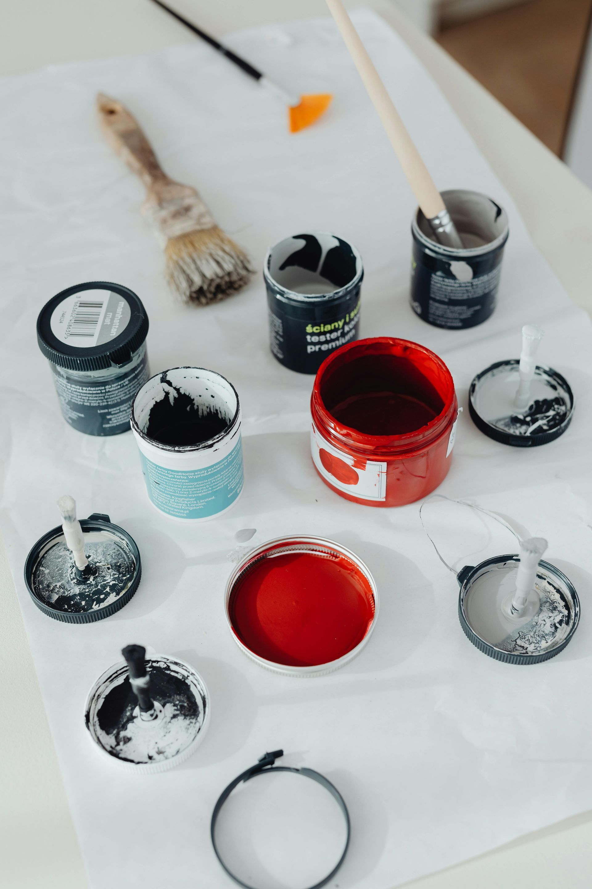 A table topped with buckets of paint and brushes.