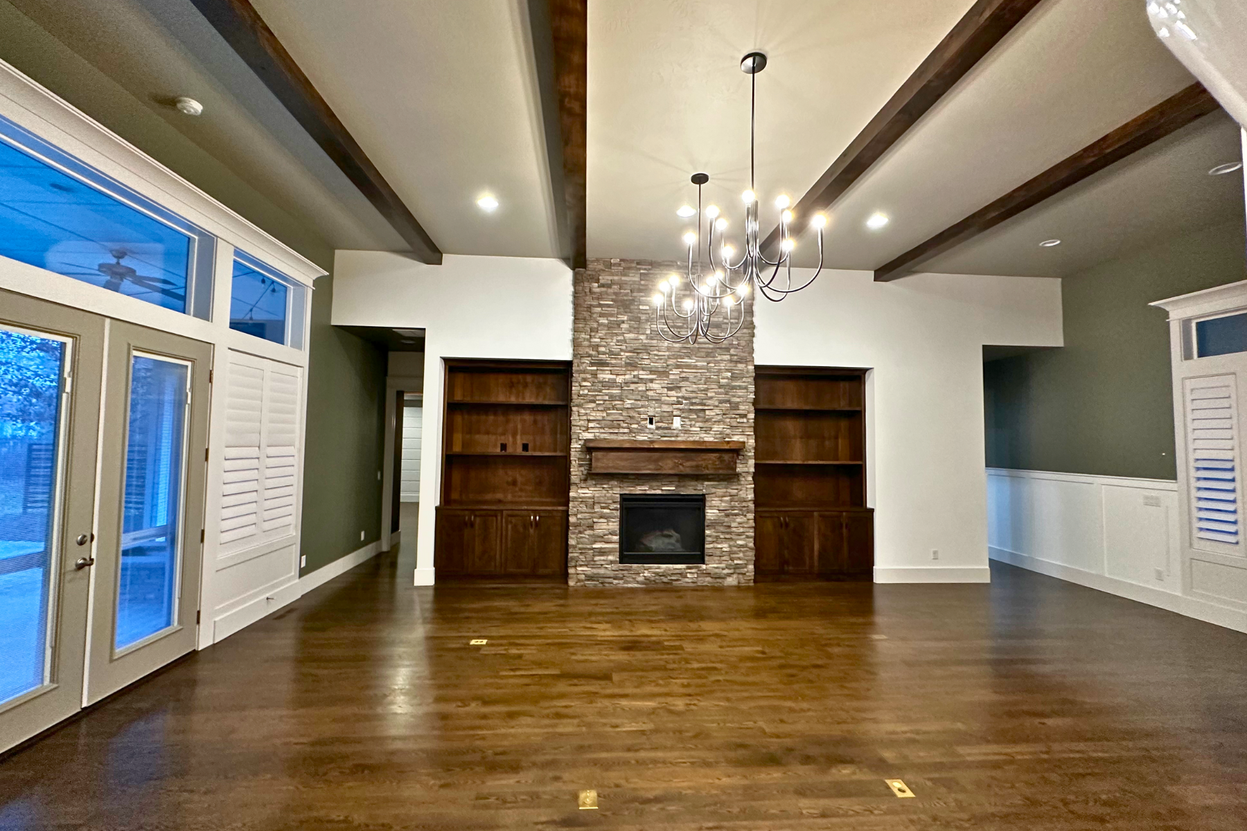 An empty living room with a fireplace and a chandelier