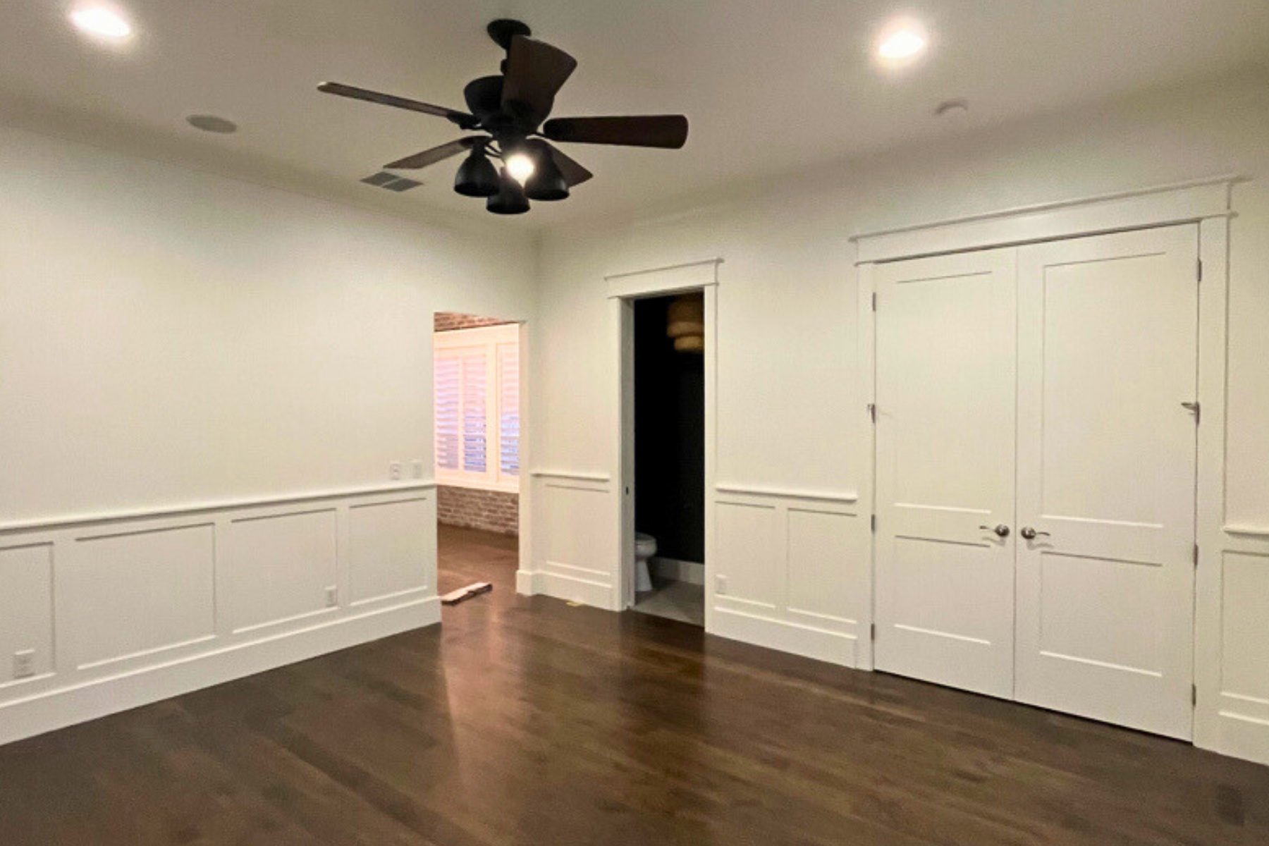 An empty room with hardwood floors and a ceiling fan.