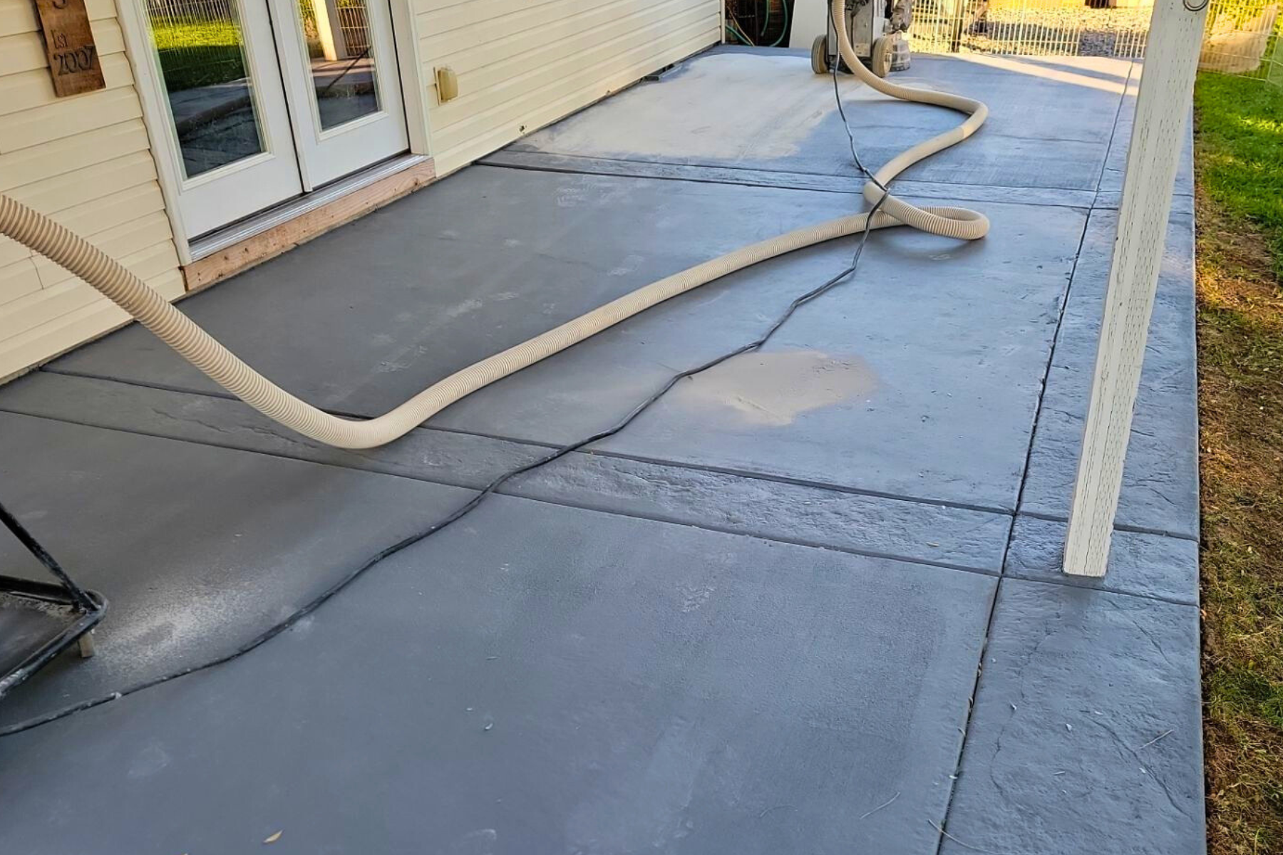 A hose is being used to clean a concrete patio in front of a house.