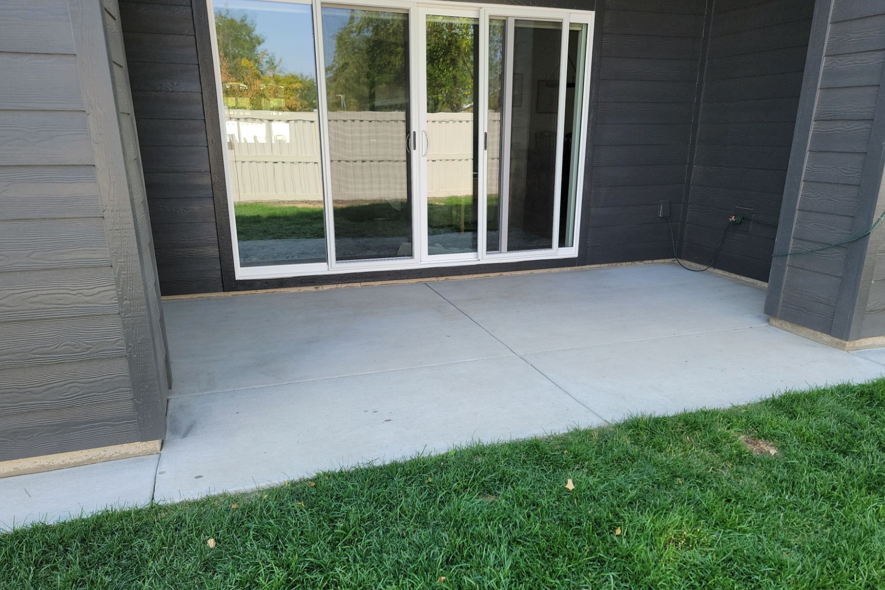 A patio with a sliding glass door in the backyard of a house.