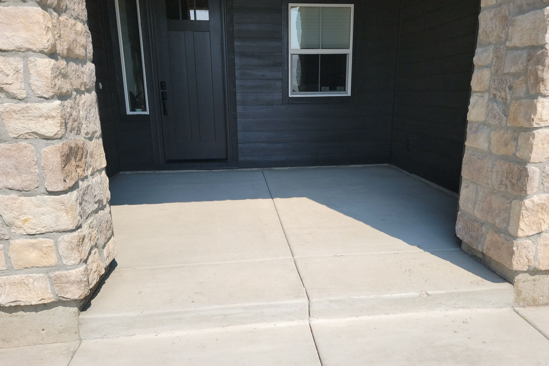 A concrete walkway leading to the front door of a house.