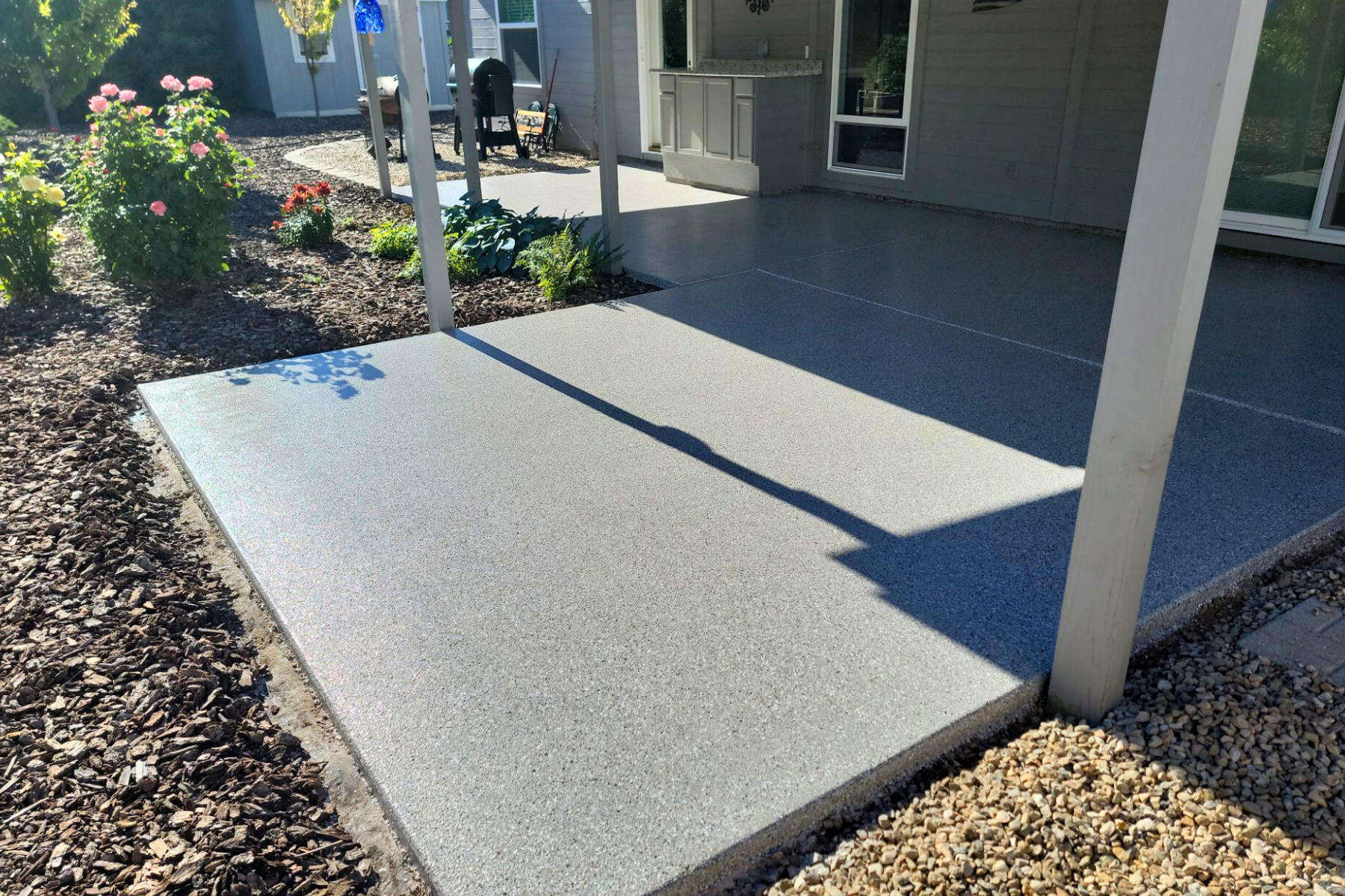 A concrete walkway leading to a house with a covered patio.