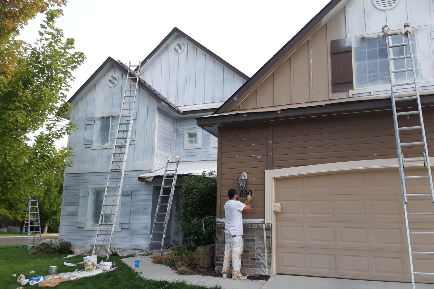 A man is standing in front of a house that is being painted.
