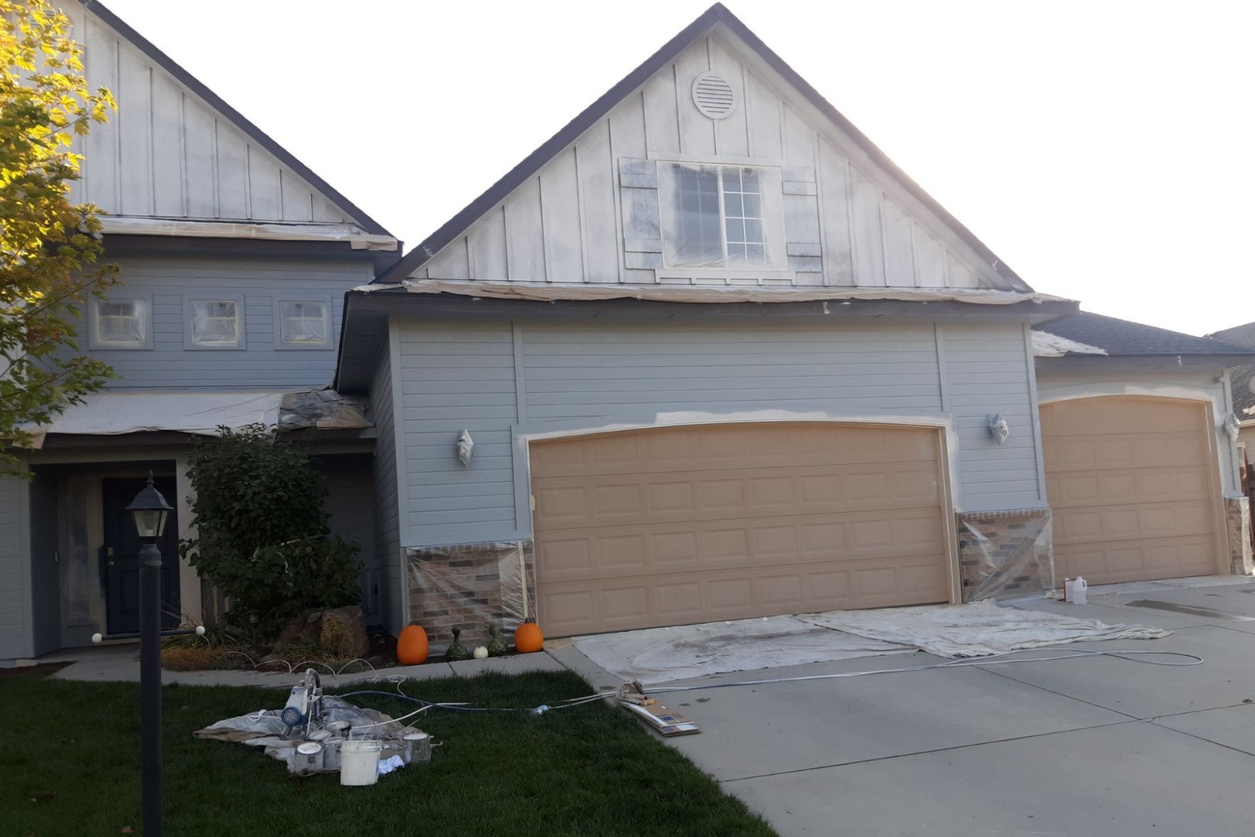 A house with two garage doors is being painted.