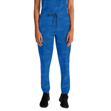 Woman in blue scrubs, drawstring pants, and black sneakers. White background.