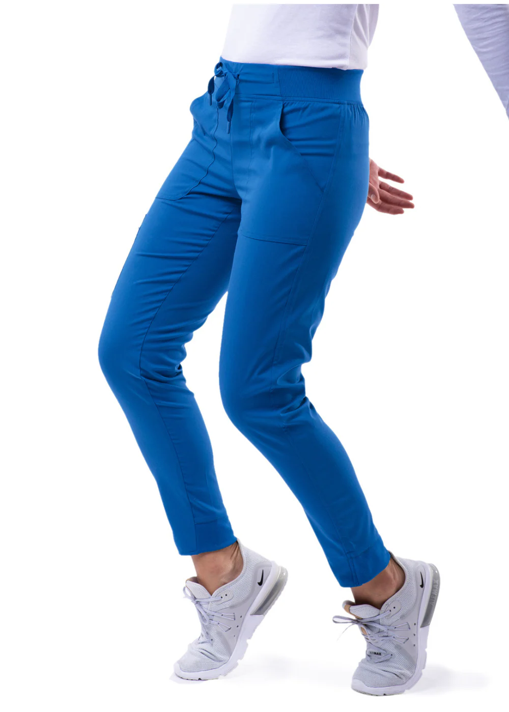 Woman wearing blue pants and white sneakers, posing.