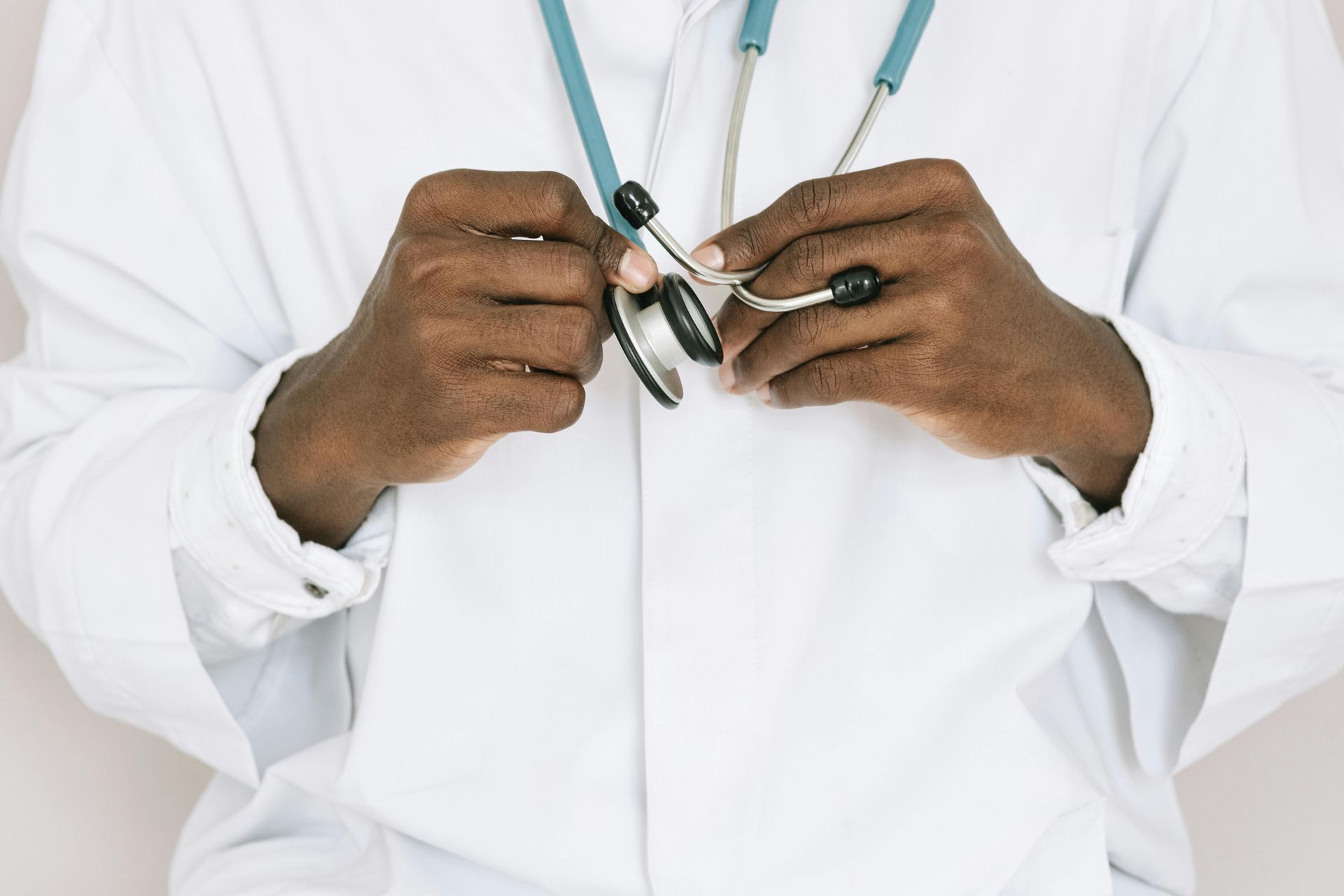 Doctor holding stethoscope, wearing a white coat.