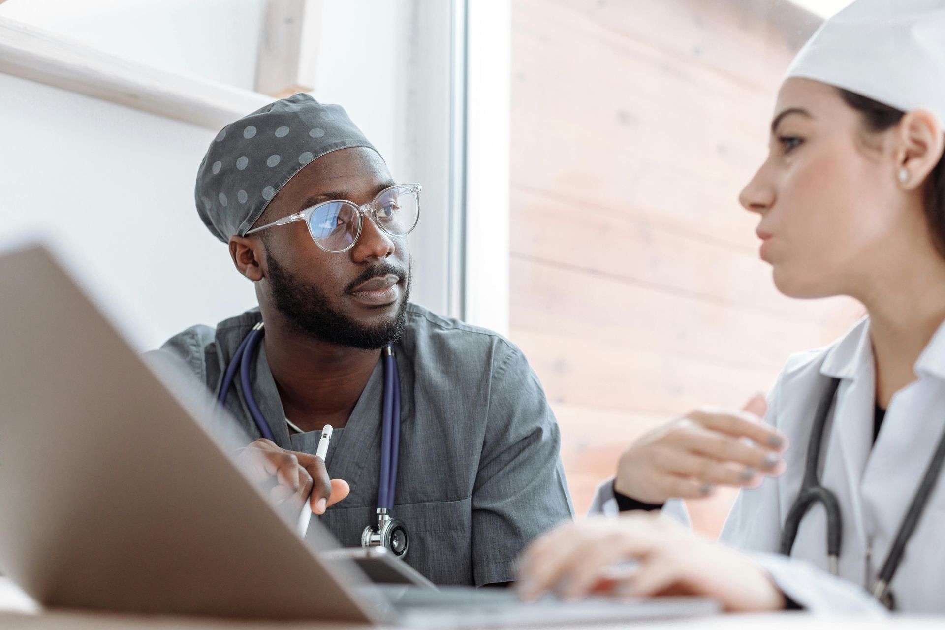 Two medical professionals, one with a laptop, engaged in discussion.