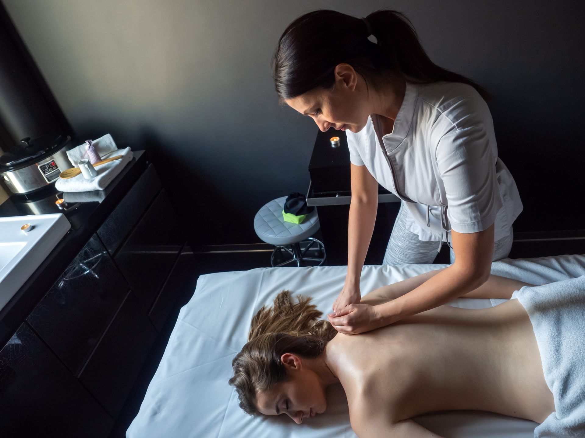 A woman is laying on a bed getting a massage from a massage therapist.