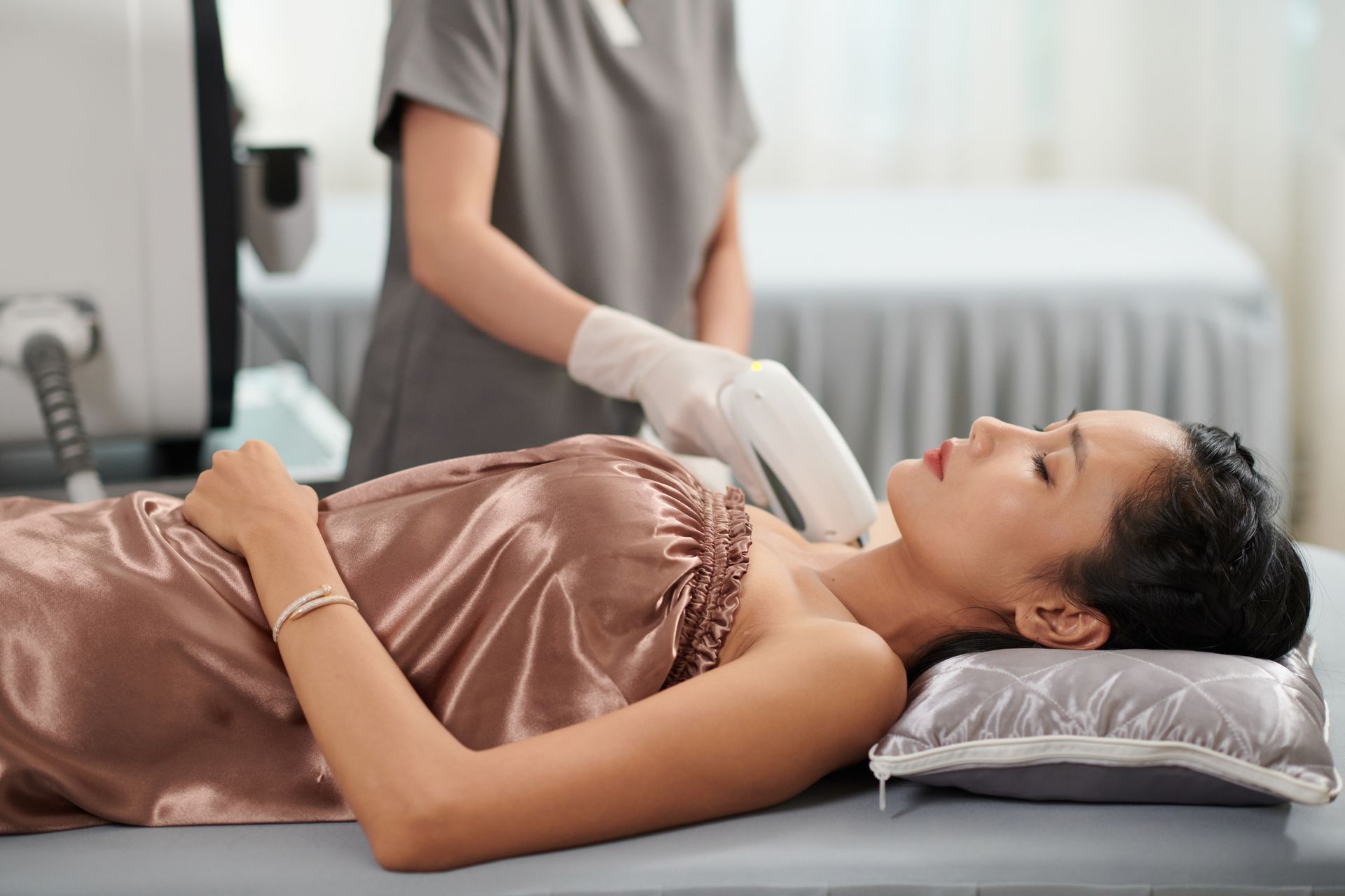 A woman is laying on a bed getting a laser treatment on her neck.