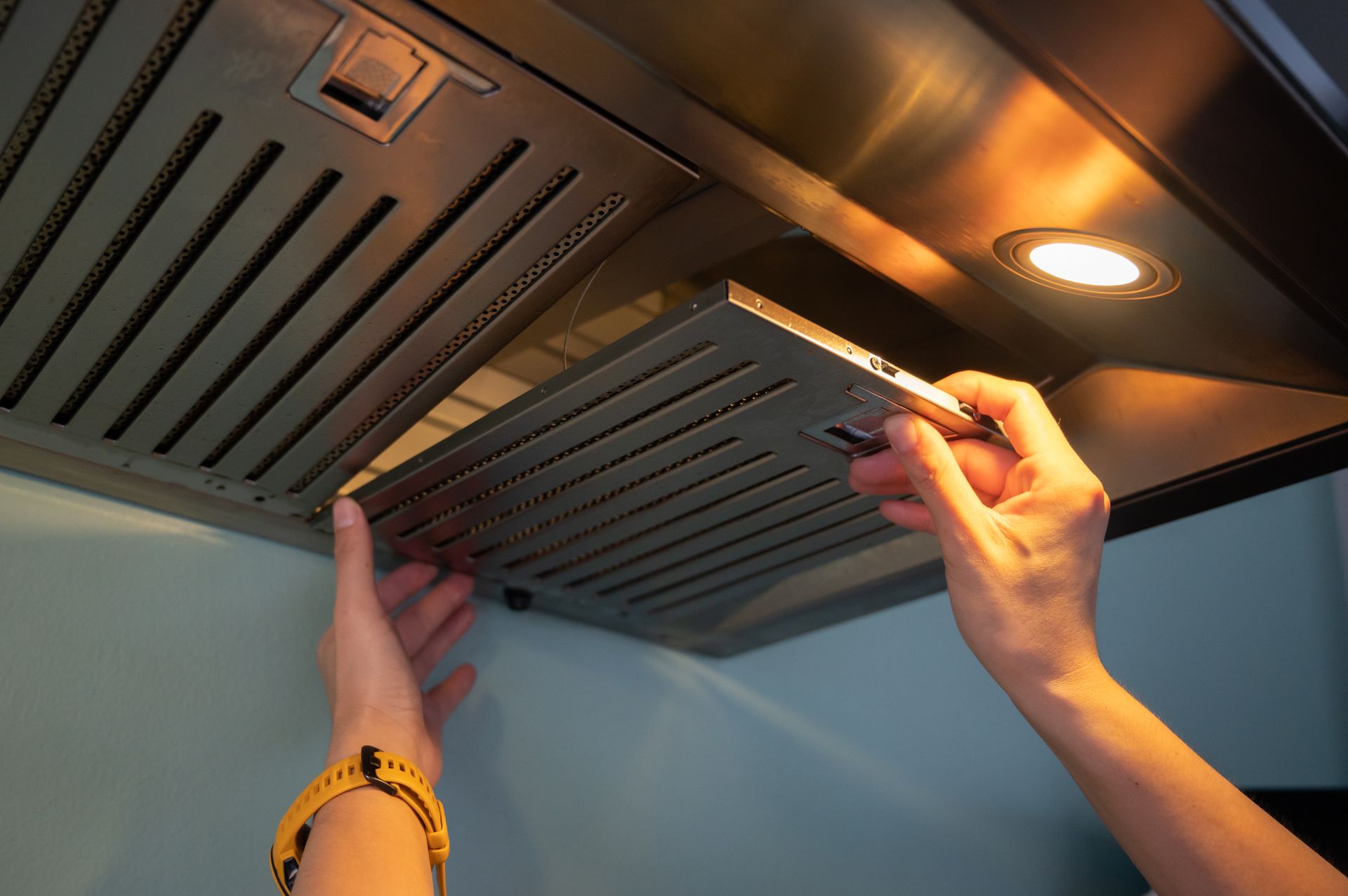 A man is removing the filter from a cooker hood.