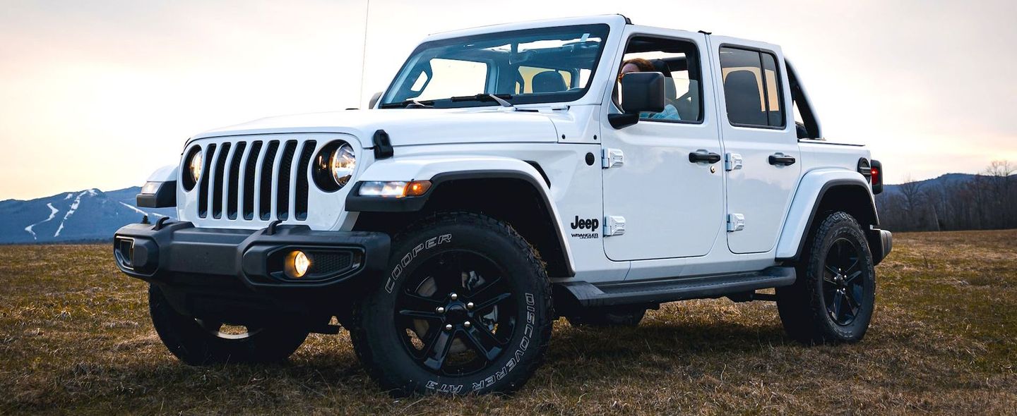 a white jeep is parked in a grassy field