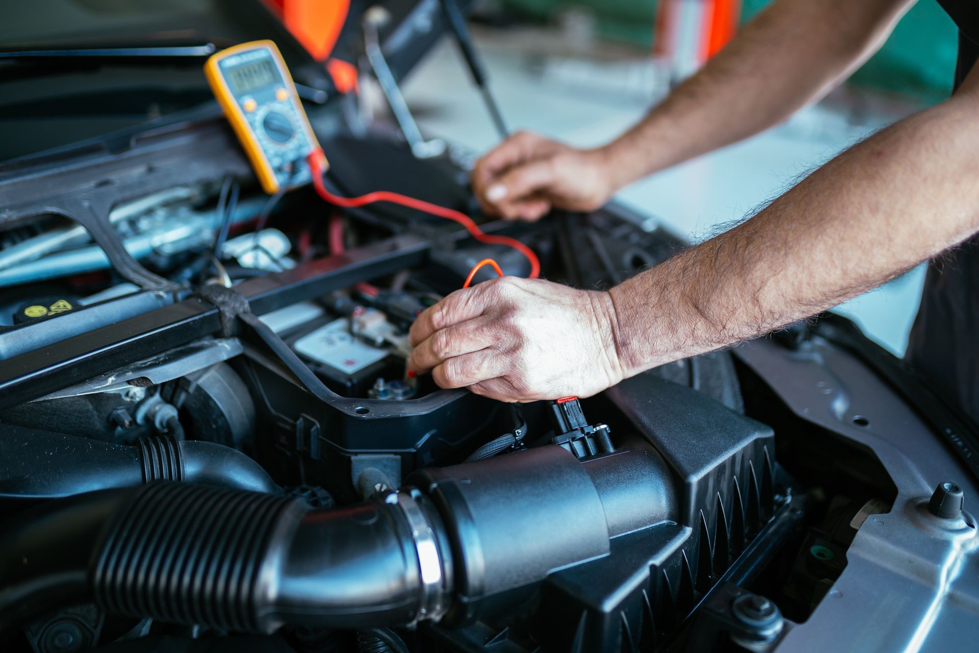 a man is working on a car with a multimeter which shows a reading of 0