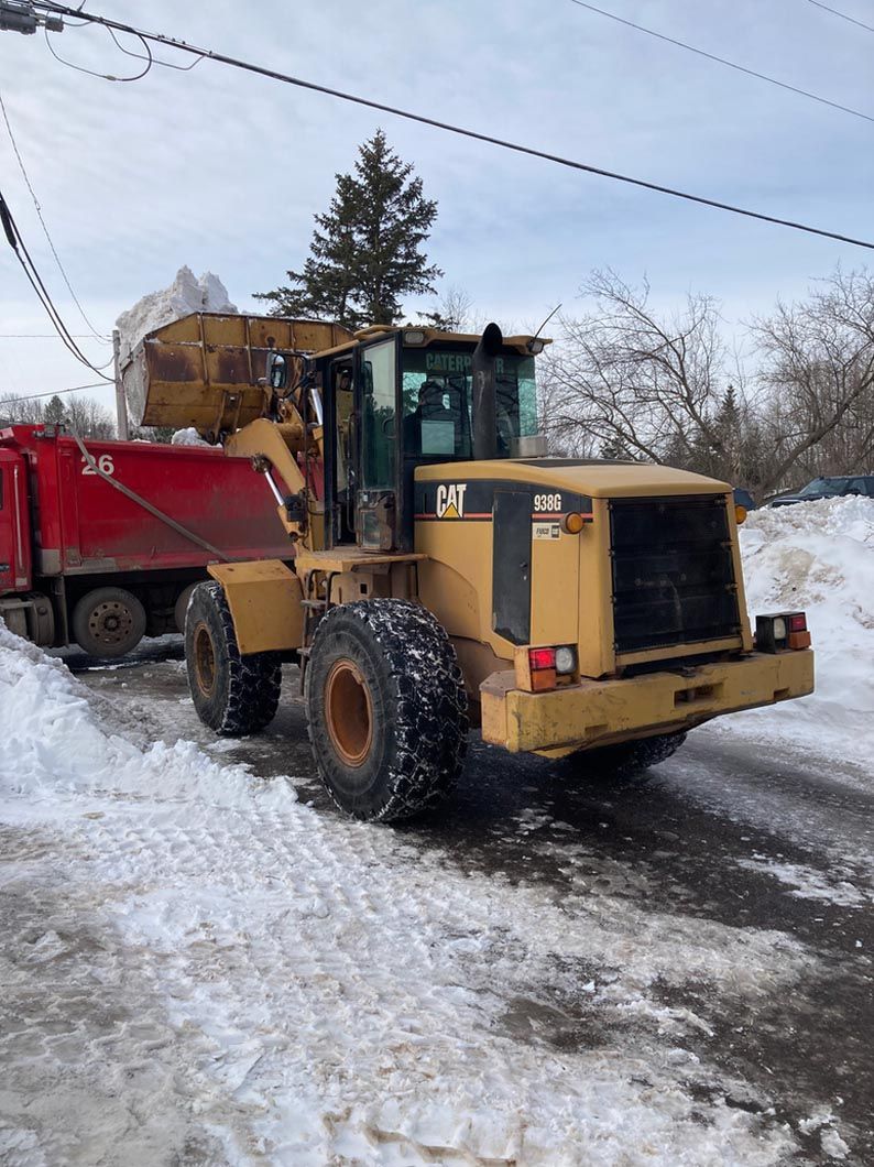 A bulldozer is parked in the snow next to a dump truck.