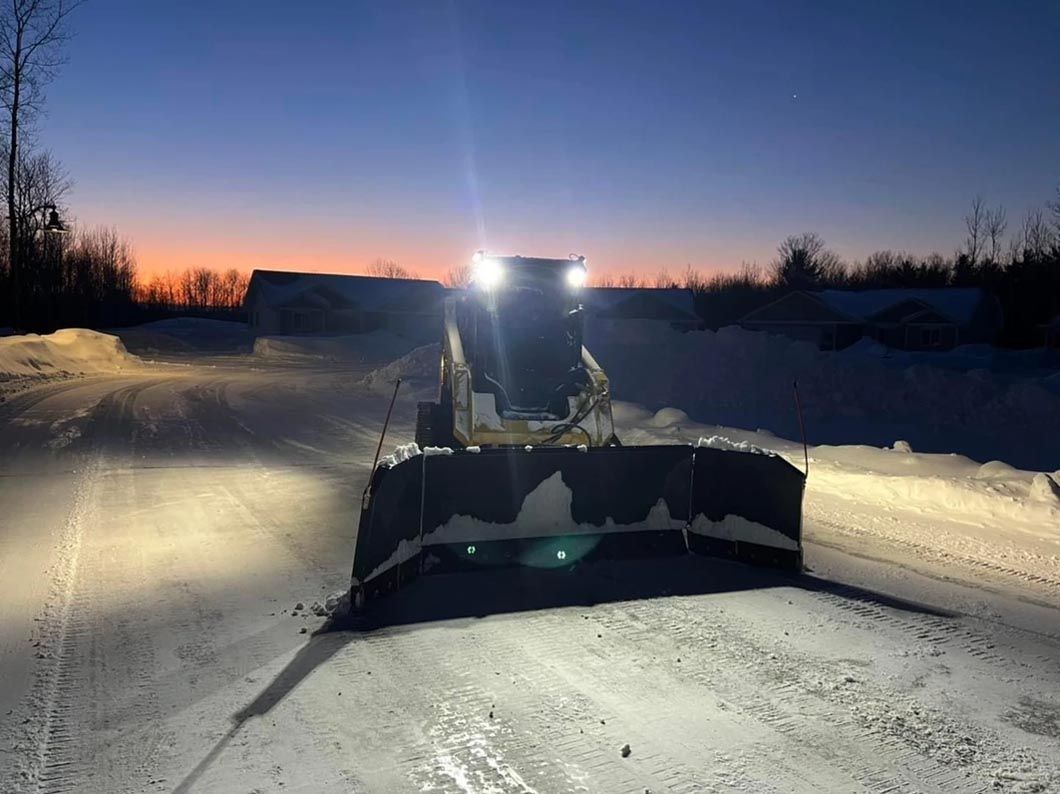 A snow plow is clearing snow from a road at night.