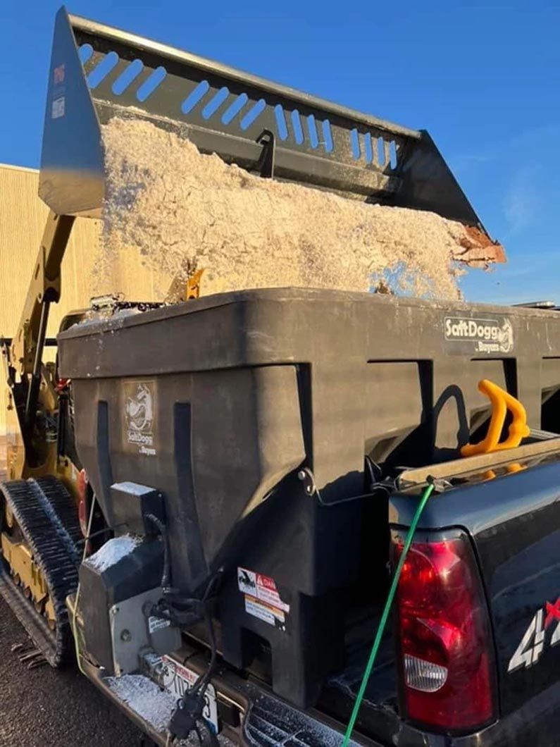 A truck is being loaded with sand by a bulldozer.