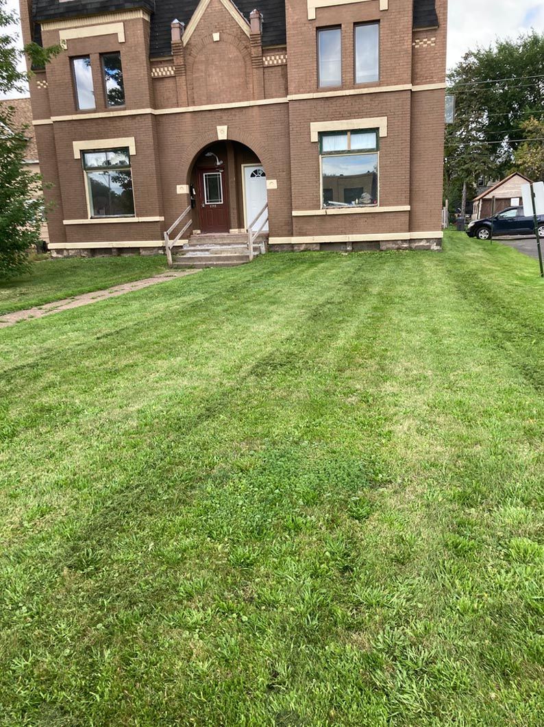 A large brick building with a lush green lawn in front of it.