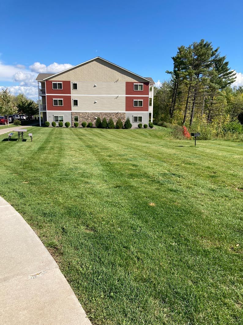 A large apartment building with a lush green lawn in front of it.