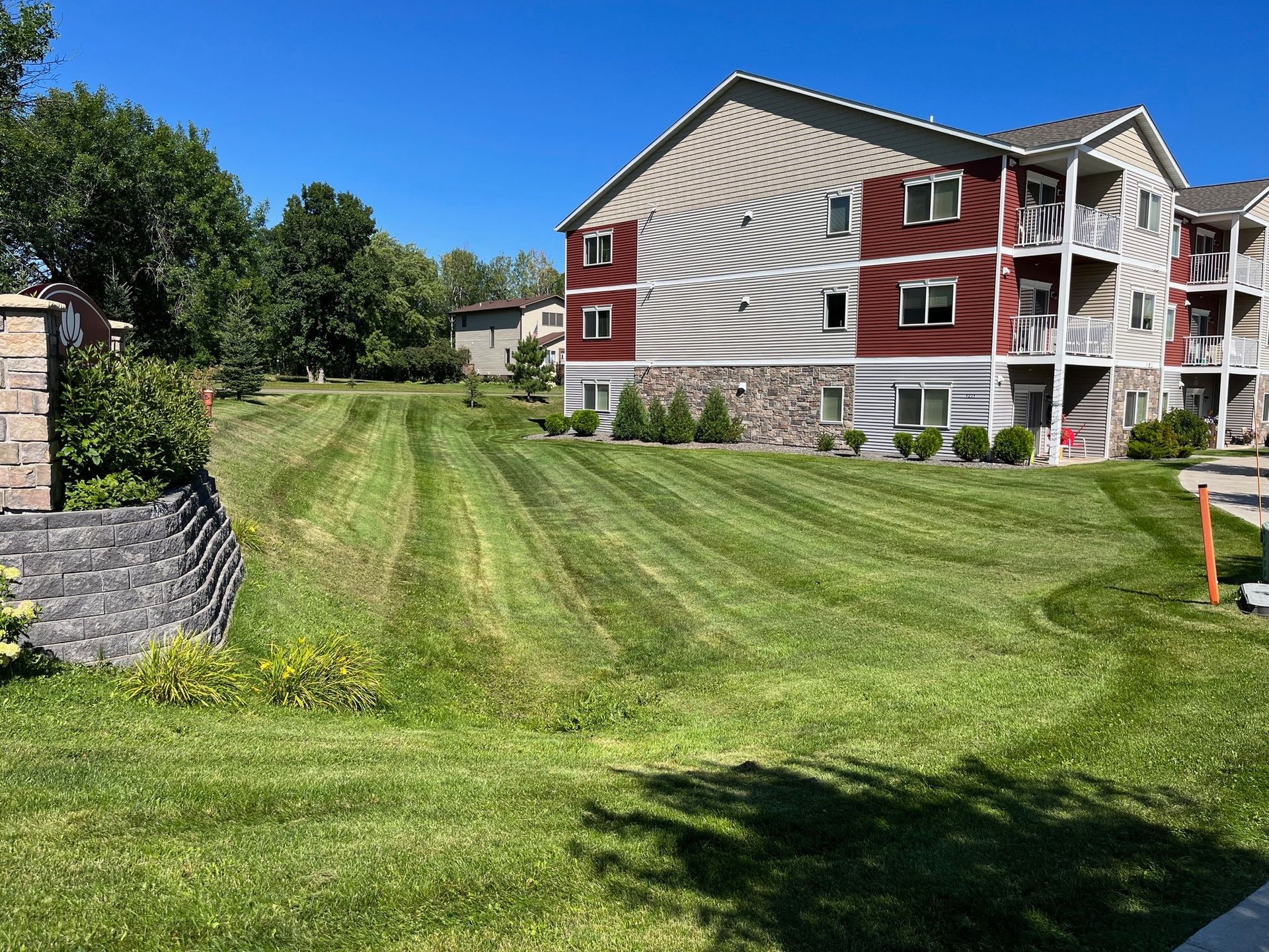 A large apartment building with a lush green lawn in front of it.