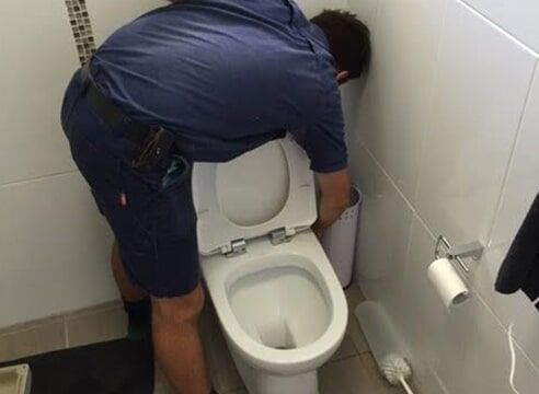 Plumber repairing a leaky toilet - Plumbing Gladstone