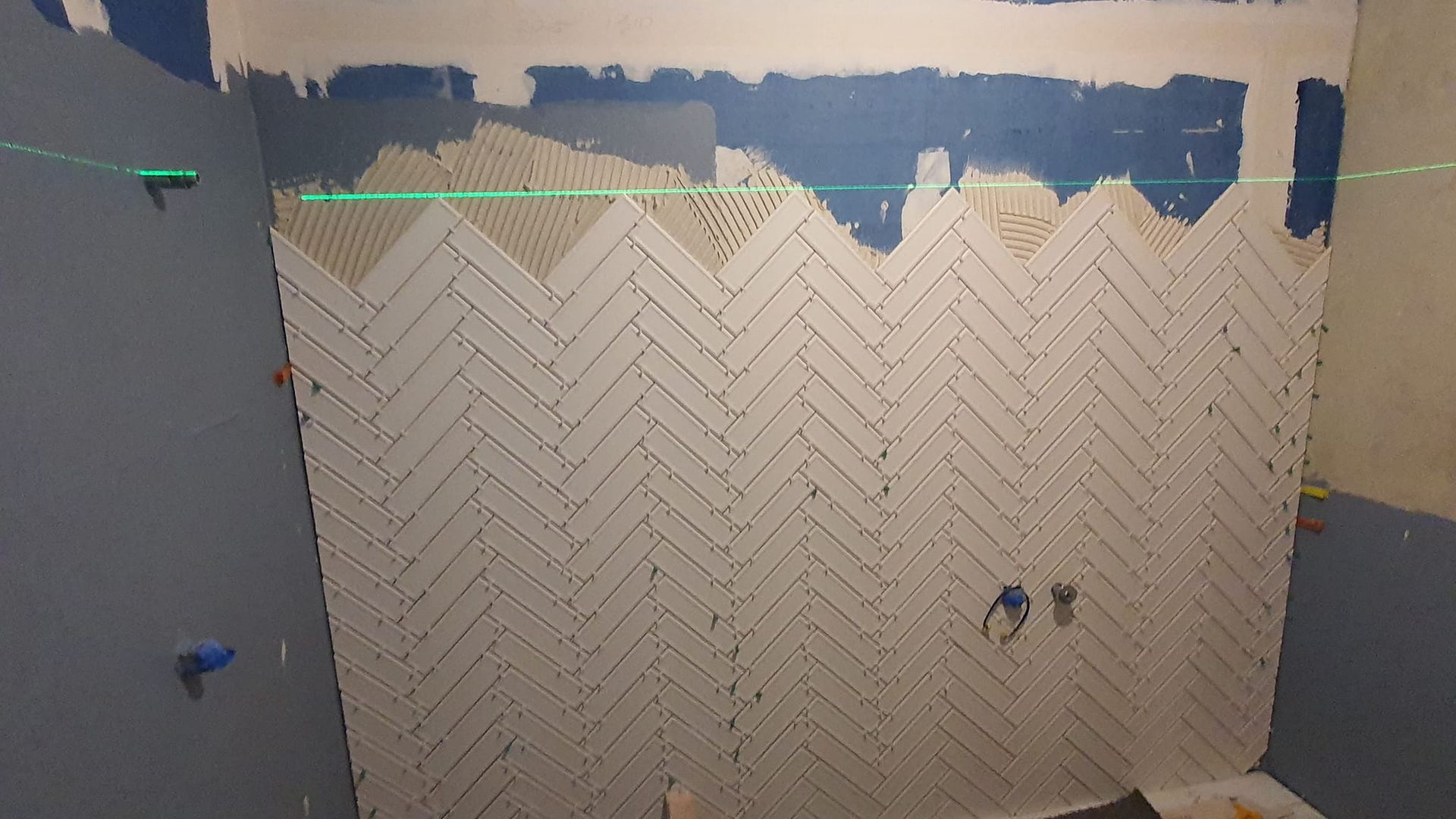 Person Wearing Gloves Placing A Tile On A Wall Covered In Adhesive — David Son Tiling in Springdale Heights, NSW