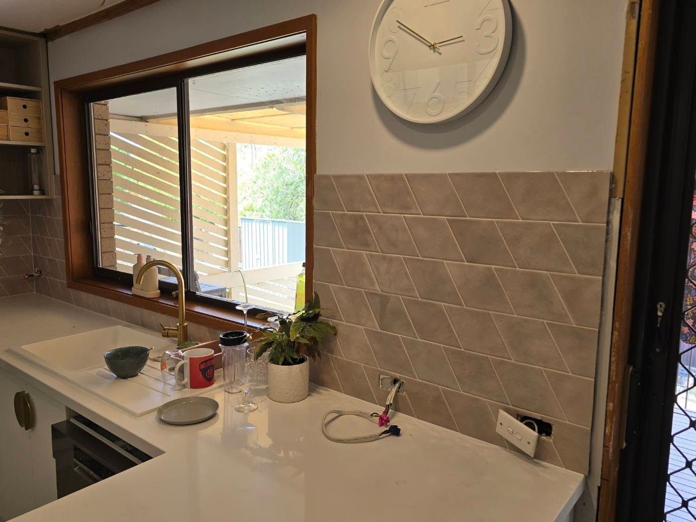 Kitchen Backsplash With Diamond Tiles, Window, Countertop, Clock, And Sink — David Son Tiling in Springdale Heights, NSW