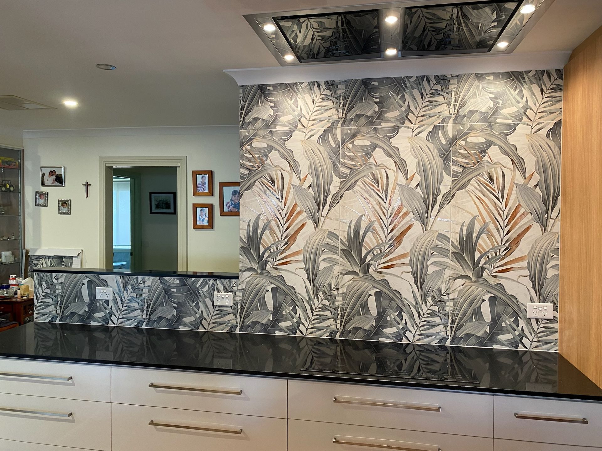 Kitchen with patterned wallpaper, white cabinets, and a dark countertop — David Son Tiling in Springdale Heights, NSW