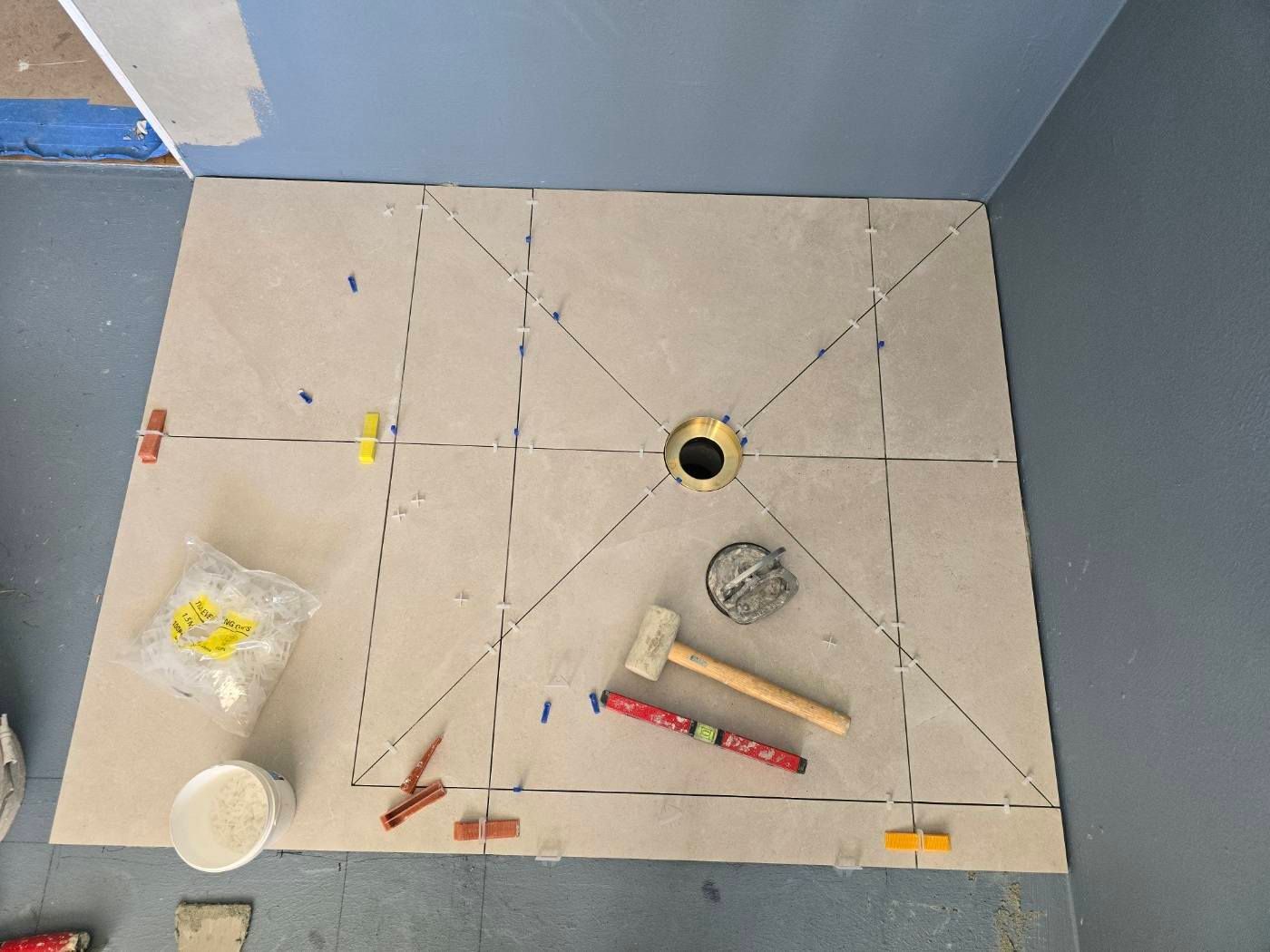 Person Using A Hammer To Install A Grey Tile On A Wall — David Son Tiling in Springdale Heights, NSW