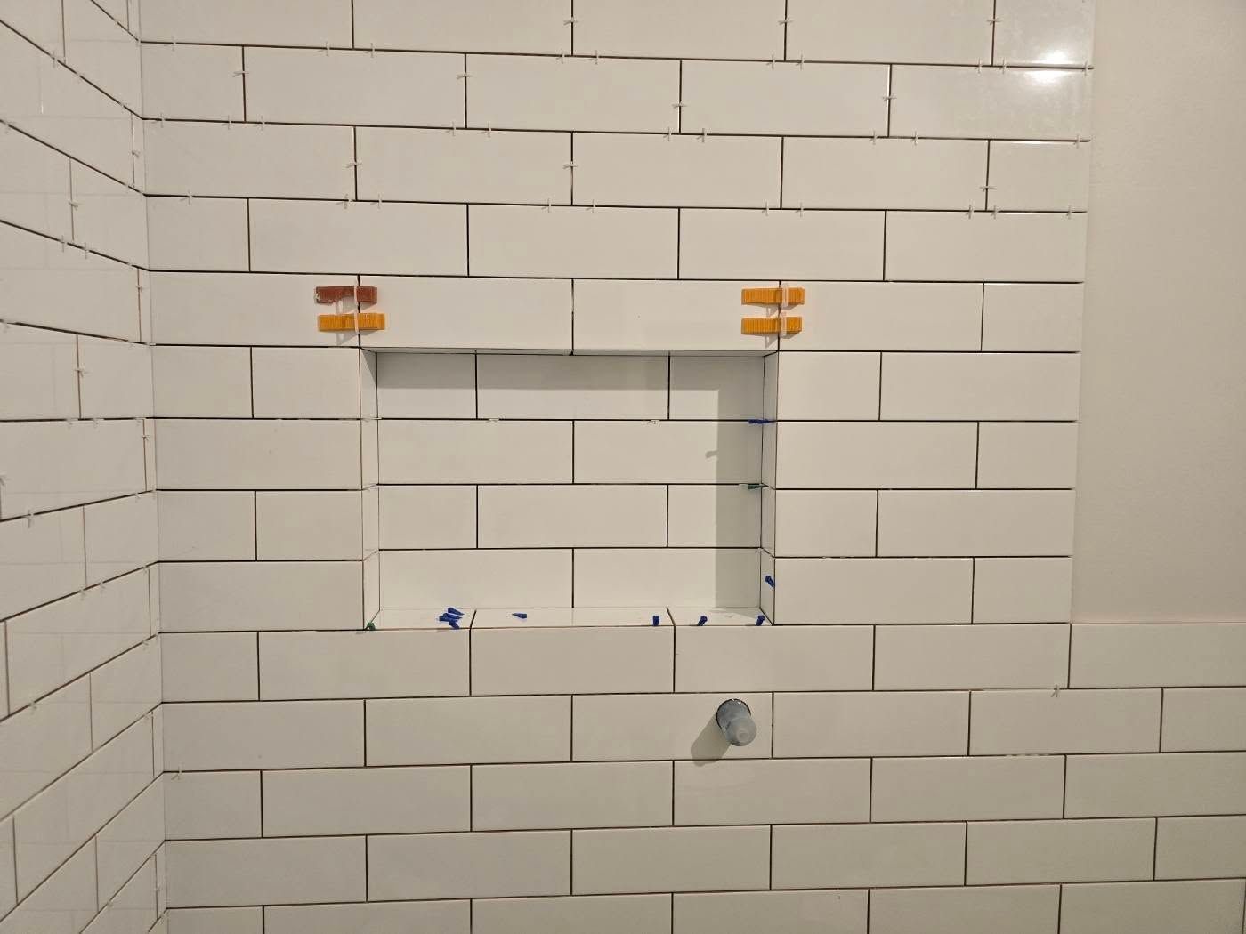 White subway tile shower wall with a recessed shelf, orange tile spacers — David Son Tiling in Springdale Heights, NSW
