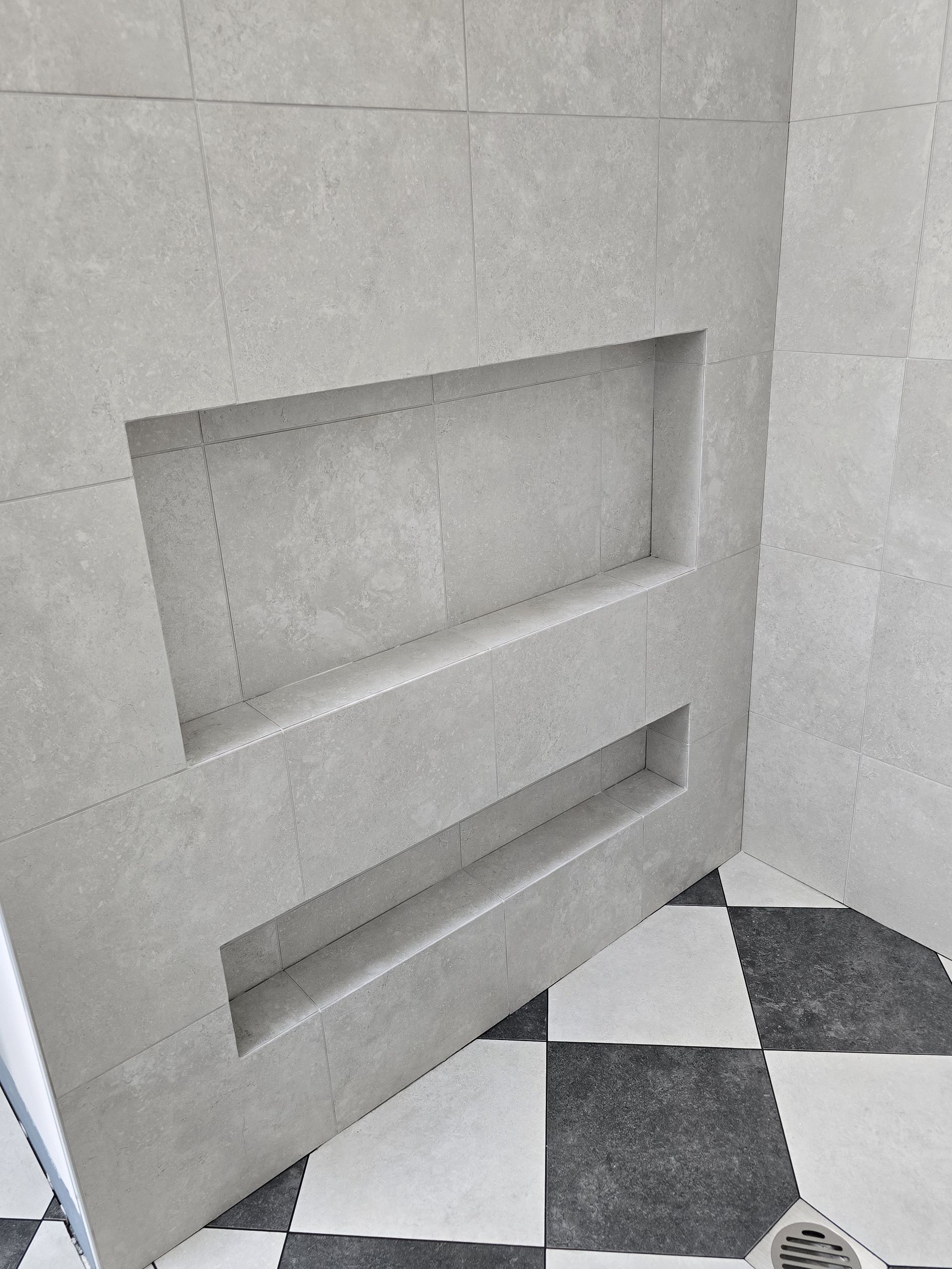 Recessed shower shelving in light grey tile, with a black and white checkered floor — David Son Tiling in Springdale Heights, NSW