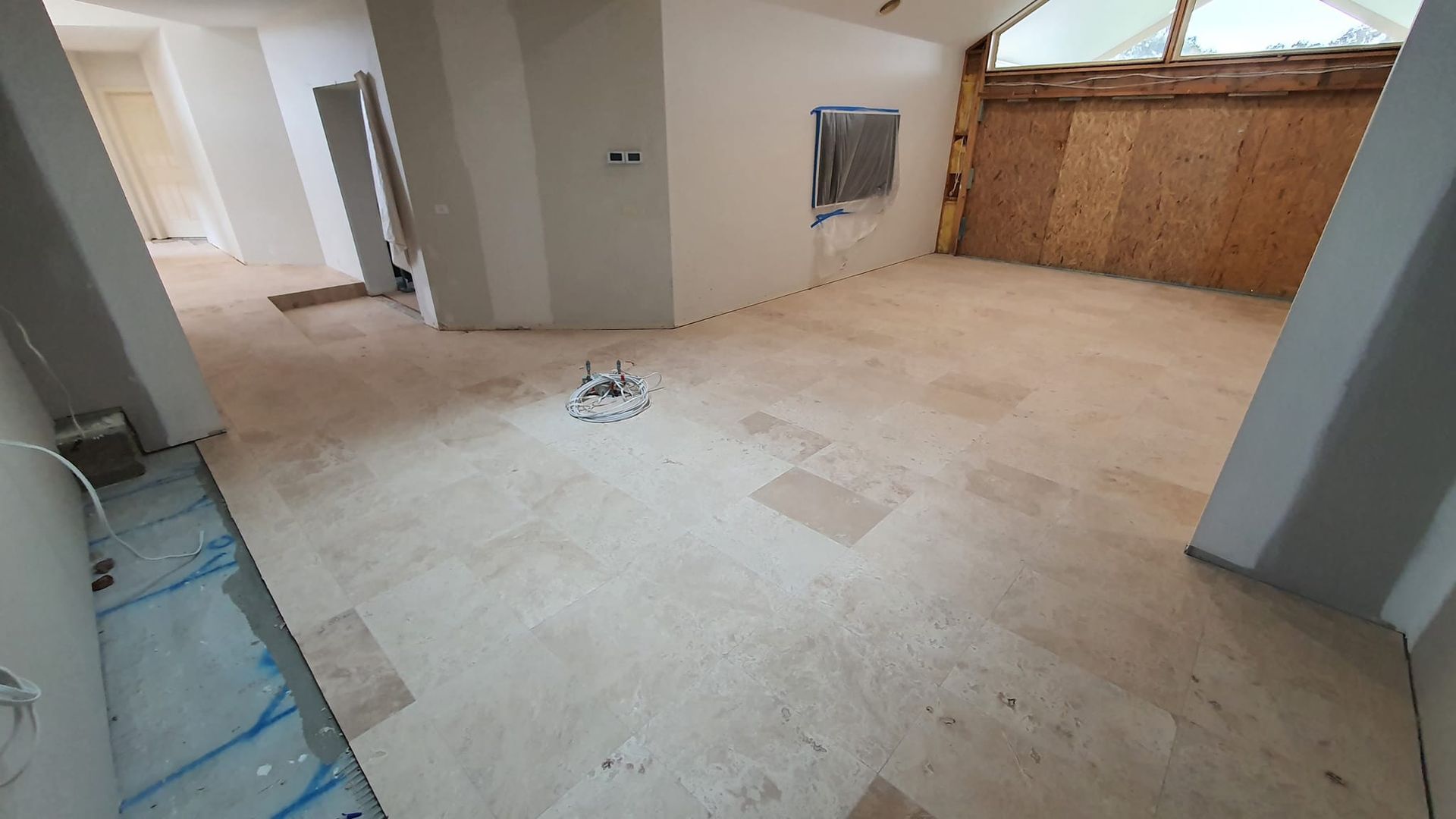 Interior of a room under construction with bare walls, flooring, and exposed utilities — David Son Tiling in Springdale Heights, NSW