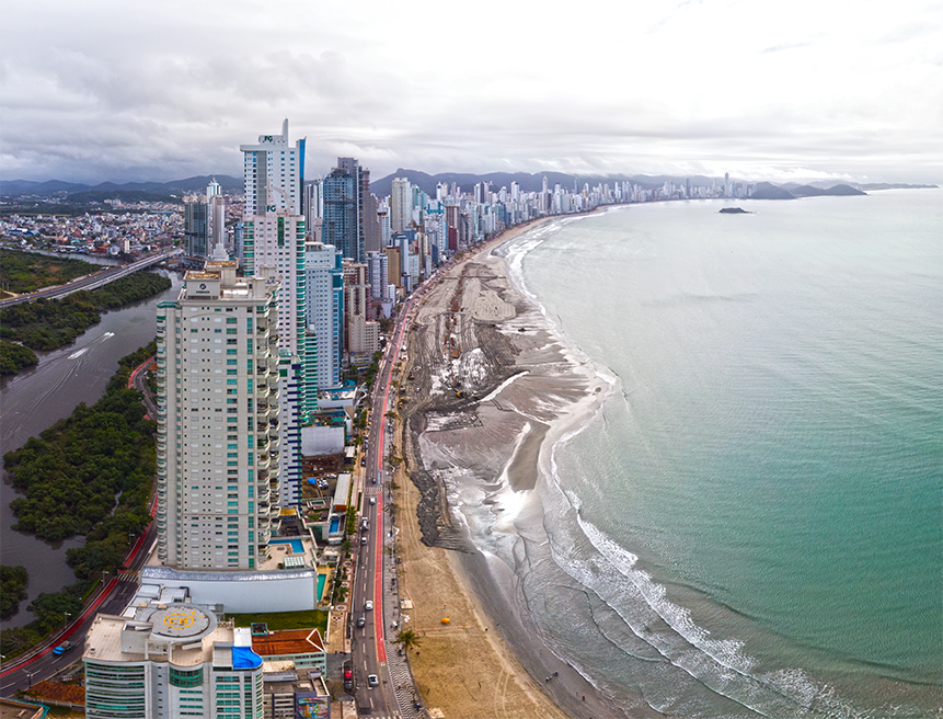 Uma vista aérea de uma praia com uma cidade ao fundo.