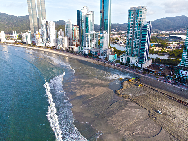 Uma vista aérea de uma praia com uma cidade ao fundo.