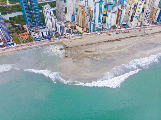 Uma vista aérea de uma praia com uma cidade ao fundo.