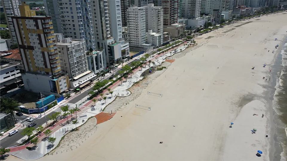 Uma vista aérea de uma praia com uma cidade ao fundo.