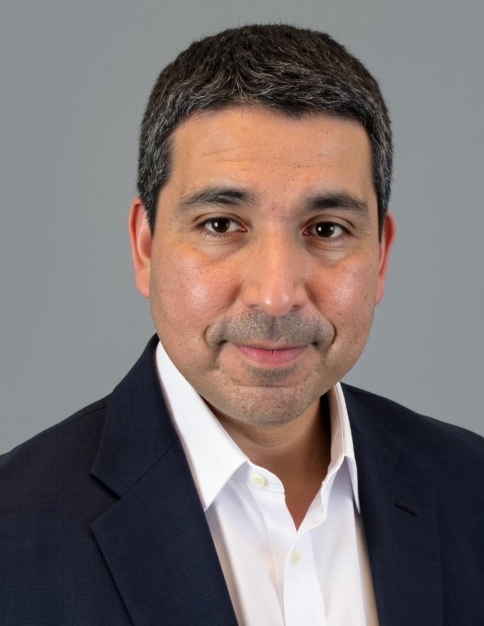 a man wearing glasses and a suit is smiling for the camera .