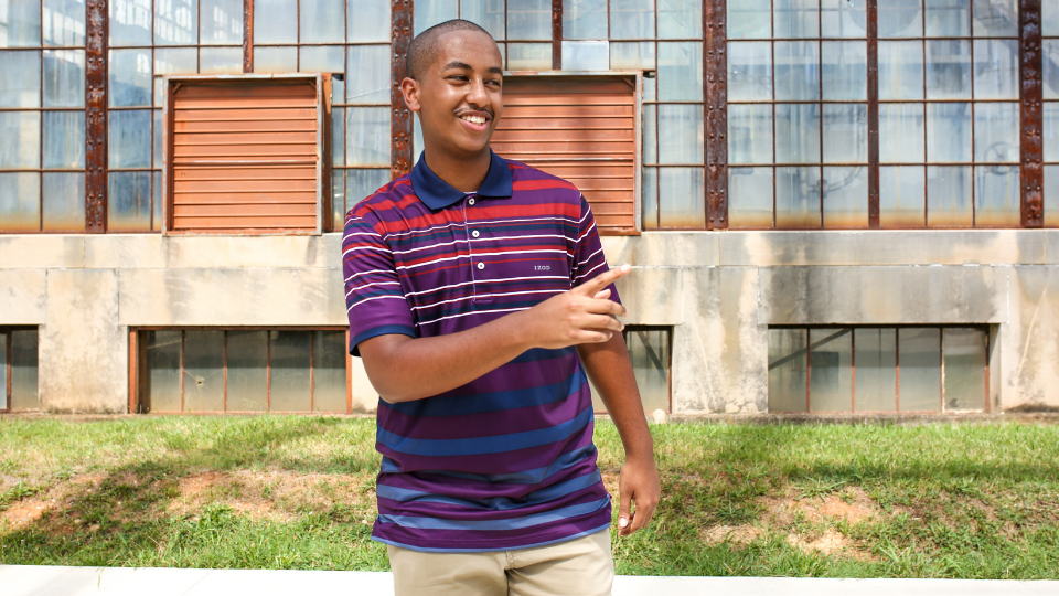 a young man in a striped shirt is standing in front of a building .