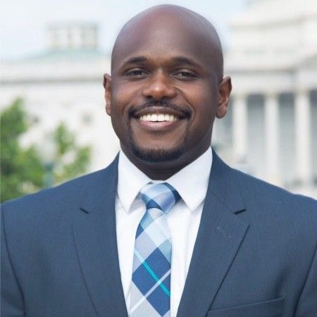 a man in a suit and tie is smiling for the camera .