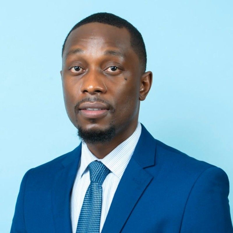 a man in a blue suit and tie is standing in front of a blue background .