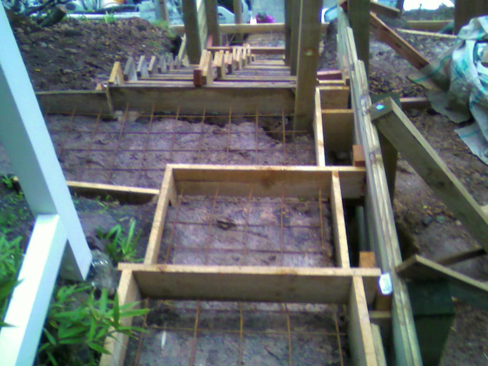Wooden forms with wire mesh framework for concrete steps being built outdoors.
